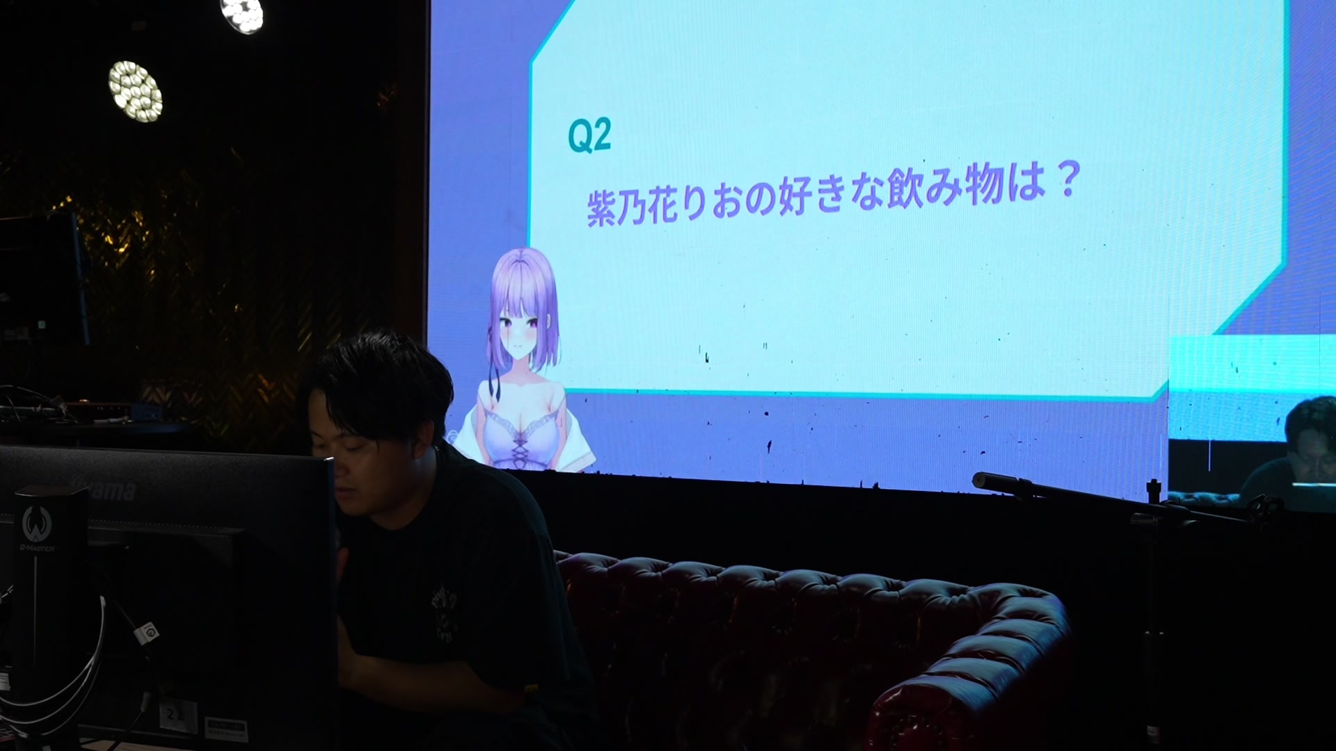 「りおクイズ」の出題画面。スクリーンには紫ノ花りおに関するクイズが映る。（当日の記録映像より）